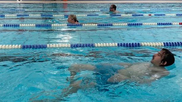 Jordan and Sophie swim breaststroke in their lanes, Jem swims backstroke.