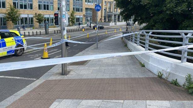 Garda tape between railings and a road crossing