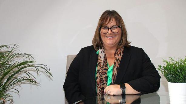 Cherie Wilson, Acorns Nurseries Director, smiling looking at the camera. She is seated at a table