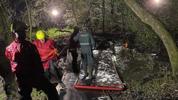 Inflatable paths are placed on the ground and over the water. Fire crews traverse them to reach the pony.