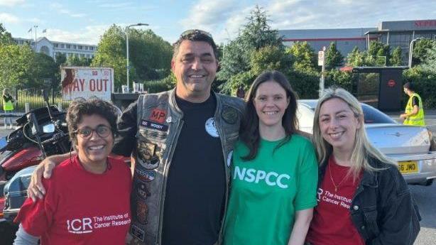 Four people stand side by side, smiling at the camera. Mr Woodcock is second from the left. He has a camouflage bodywarmer on, the other people are wearing either red "Institute of Cancer Research" T-shirts or green "NSPCC" branded T-shirts.