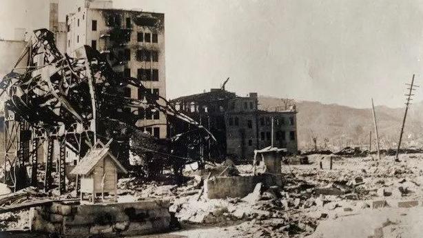 A black and white photograph of Hiroshima in 1945 to capture the devastation in the aftermath of the atomic bomb. It shows buildings destroyed and rubble and pieces of twisted metal that were once part of buildings.