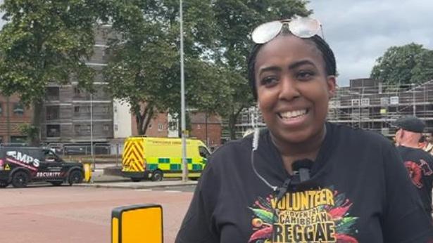 A woman wearing a Coventry Caribbean Reggae Festival t-shirt in the street