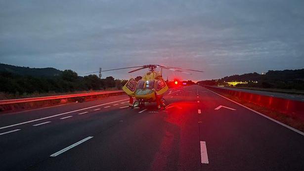 A medical helicopter landed in the middle lane of the M5 motorway. The sky is still dark as dawn hasn't broken yet. 