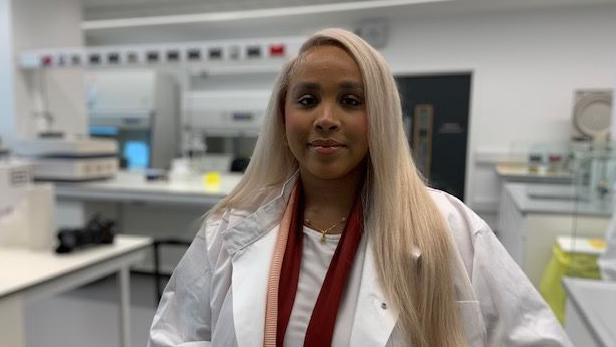 Asia Sharif wearing scrubs on a tour of the cancer research facility