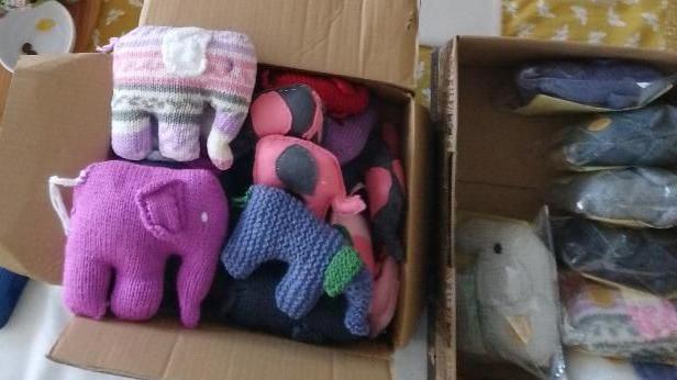 Knitted elephants of multiple colours in a cardboard storage box