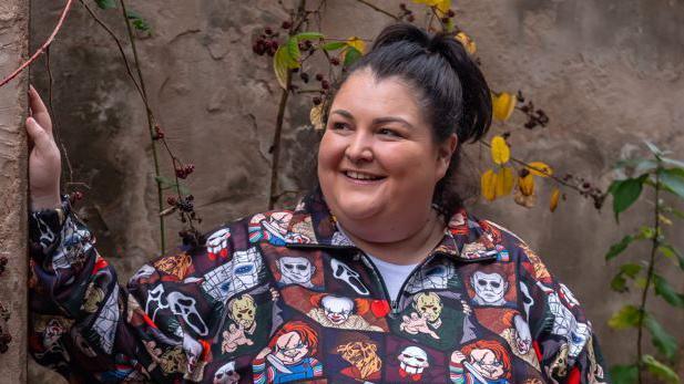 Jo Frost standing in front of a wall smiling.