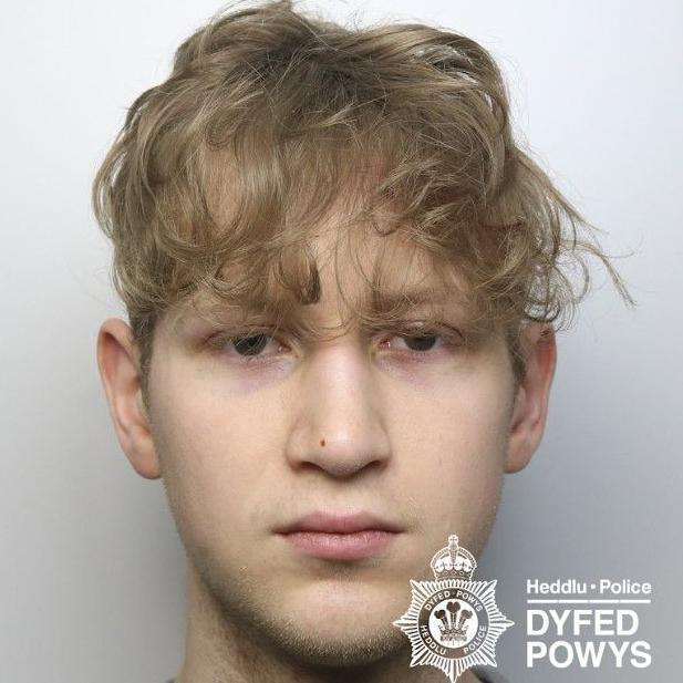 A young man is pictured with blonde hair looking at the camera