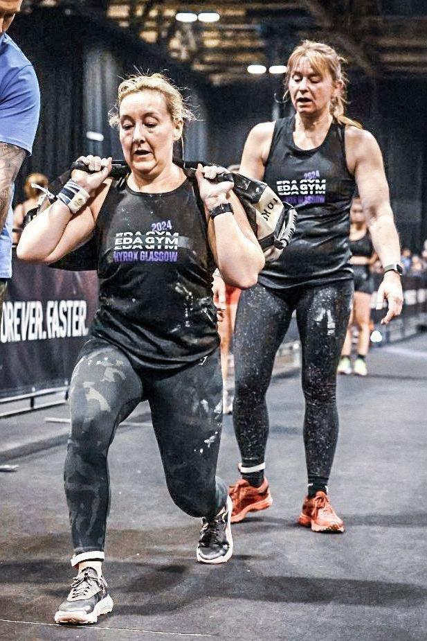 Leigh completes a lunge with a weighted sand bag on her back. Her race partner Wiki follows behind her waiting for her turn