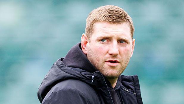 Finn Russell standing on the pitch wearing a black coat looking over his right shoulder before Bath v Leicester.