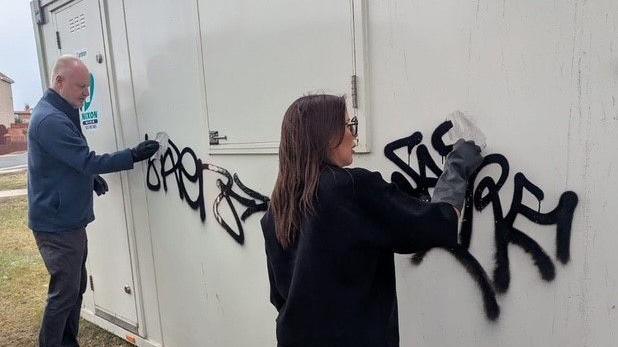 Michael Hartnack (left) and Nichola Austin-Ratcliffe scrub graffiti from a temporary structure erected around the war memorial site.