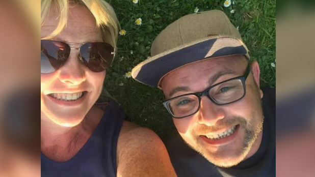 Julian wearing a cap and his dark framed glasses, smiling with his mum Jan Hoska who is wearing sunglasses and a navy vest top with a big smile on her face