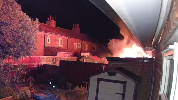 A line of houses with a bright orange flame engulfing some of the homes