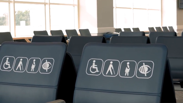 Blue hard seats with a signs representing wheelchair users, pregnancy, visual impairment and a person walking with a stick sign.