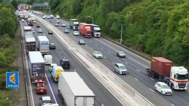 The M1 motorway with traffic building up on both lanes, showing cars and lorries on the road. There are several lanes of traffic.