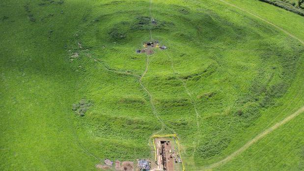 The site of Tlachtga in a drone image, showing a large green area which dips down showing small paths and patches of mudded areas where bonfires would have been lit. 