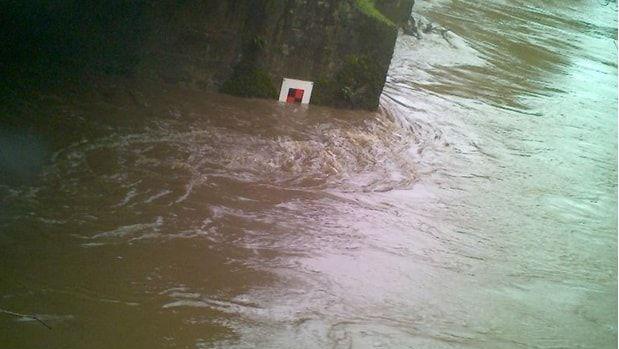 Image showing flooding reaching the closure marker on the Barnstaple-Crediton railway line. The water is brown and murky.