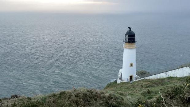 Maughold lighthouse, which sits on the edge of a cliff with the Irish Sea stretching out in front of it.