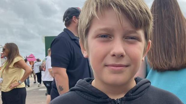 Young boy, Alfie on Clacton Pier with people around him. 