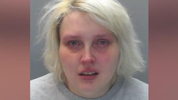 A mugshot of Danielle Massey who has short, blonde hair. It looks like she's crying and has her mouth open.