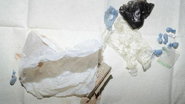 Small blue bags containing drugs on top of a white tissue. 