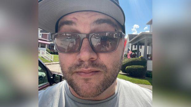 Timothy Quinn wears sunglasses and a black hat in a selfie style photo