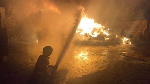 Firefighter using a water hose on a large fire at a scrap metal unit 