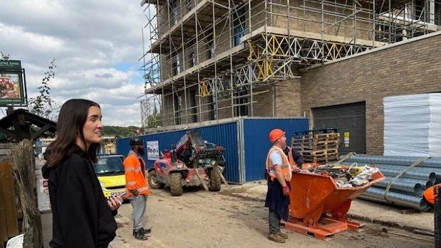 Property being built with scaffolding around it with two builders in orange clothing looking up at the building.