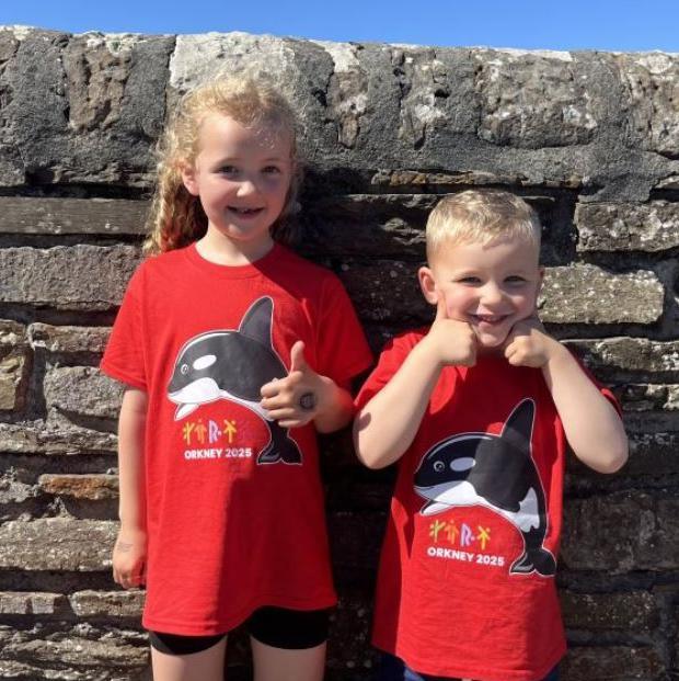 Two young children wearing t-shirts with an orca on them, the mascot for the island games