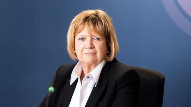 Baroness Hallett in front of a blue backdrop featuring the pink, purple and white Covid-19 inquiry logo.