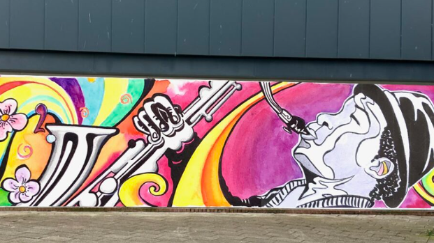 A mural showing a man playing a saxophone. It includes bright colours such as pink, orange and yellow.