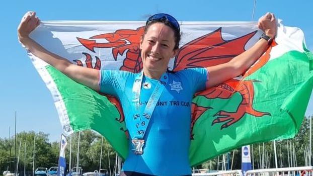 Laura Butcher crosses the finish line wearing a Welsh flag