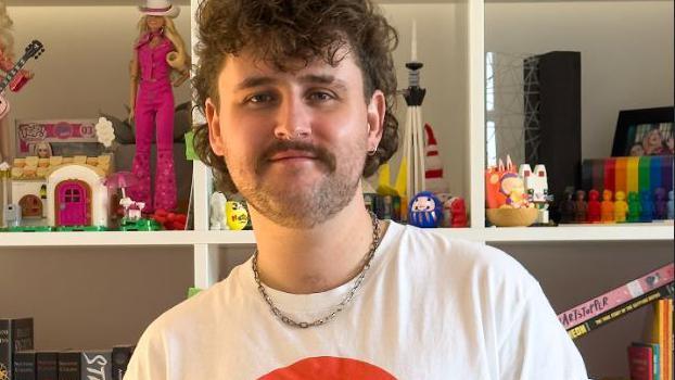 Gareth Clarke has curly brown hair and is wearing a white T-shirt.