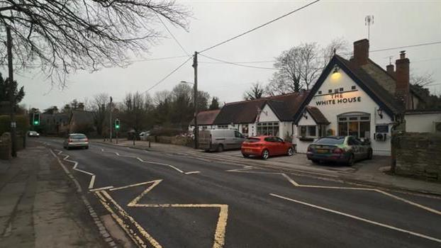 Road through a village with a white pub on the right