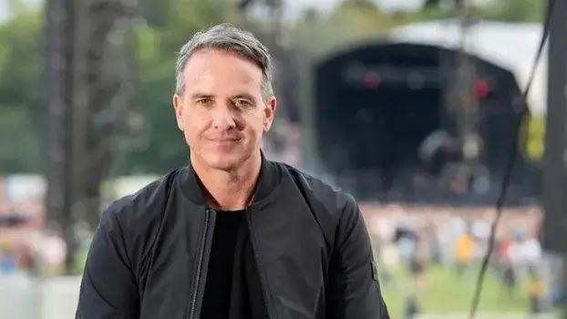 Sacha Lord wears a black bomber jacket and t-shirt while stood in front of a crowd of people at Parklife festival 