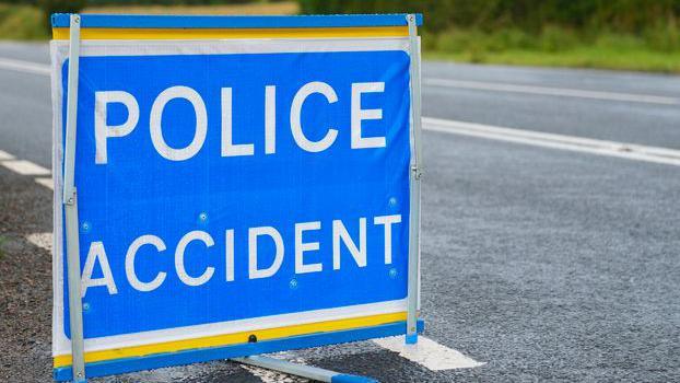 A sign saying police accident. It is blue and place on the side of a road.