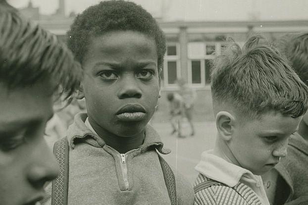 A close up of four boys, one of which is looking at the camera, wearing a quarter zip 