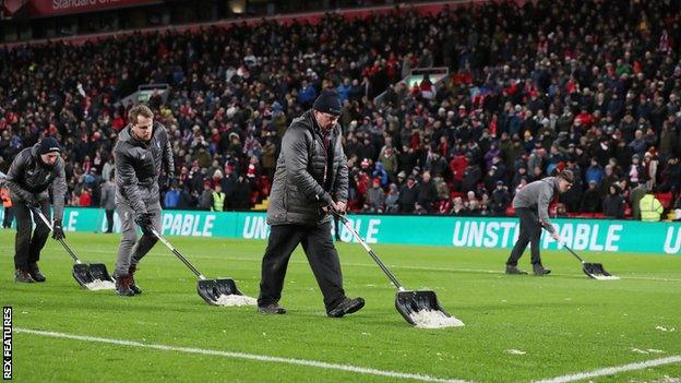 Liverpool groundstaff clear the pitch of snow at half time