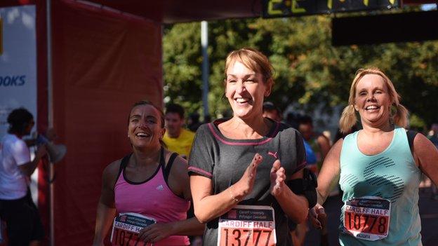 A woman claps as she finishes the Cardiff Half Marathon