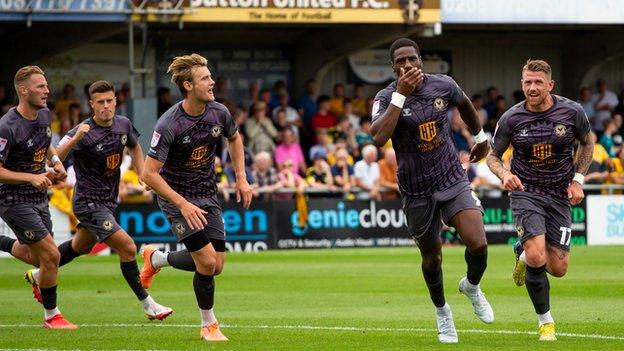 Omar Bogle celebrates with Newport teammates after scoring at Sutton