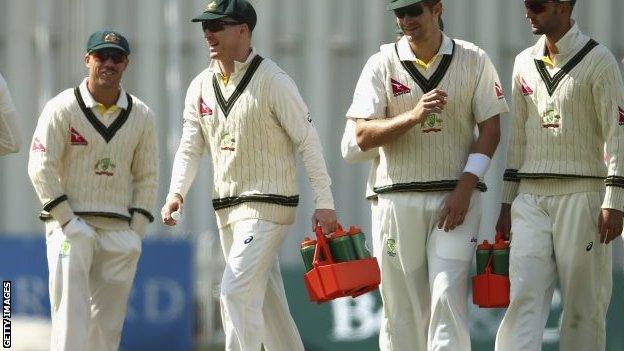 Australia's Chris Rogers (second left) carries drinks on to the field against Derbyshire