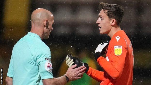 Gillingham goalkeeper Jamie Cumming picked up one of the objects thrown at him at the Abbey Stadium