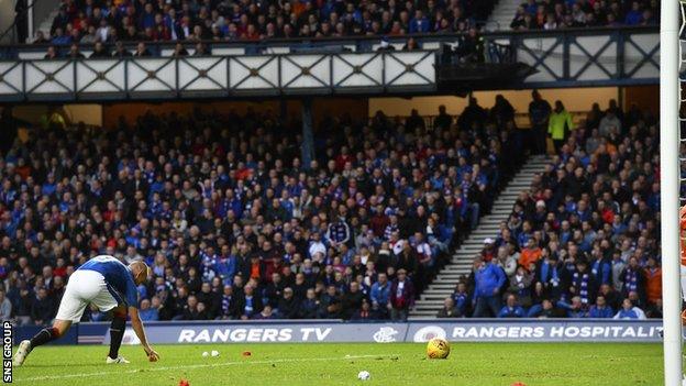 Rangers striker Kenny Miller collects objects that were thrown onto the pitch at Ibrox