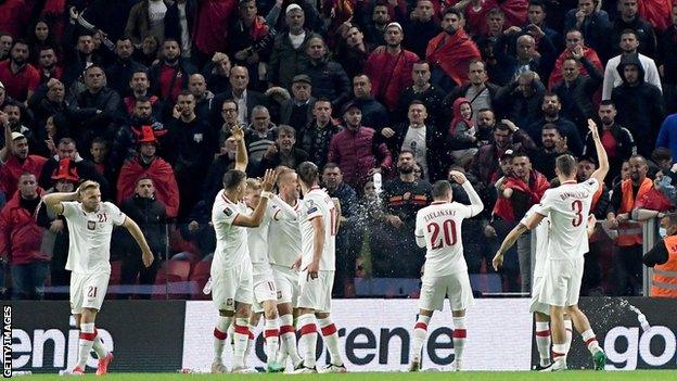 Poland players protect themselves from bottles being thrown at them after scoring