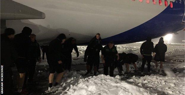 Northampton Saints players, staff and fans try to help clear snow around their plane