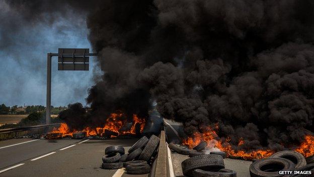 Ferry workers burn tyres on both lanes of a road leading to the port of Calais on 31 July 2015