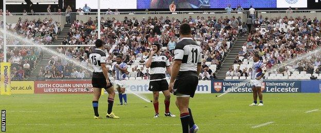 Players look on after the sprinklers stop plat at the Olympic Stadium