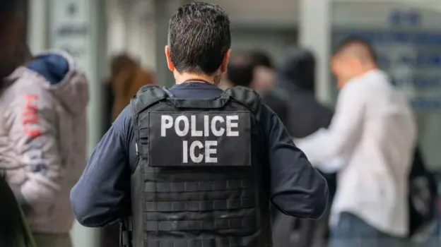 Photo shows back of police officer wearing Police Ice vest