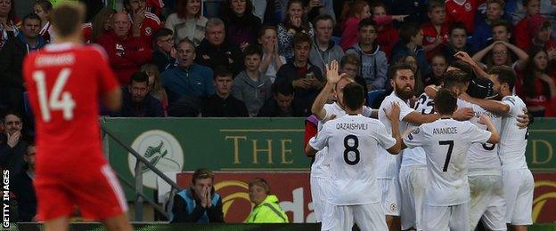 Georgia celebrate their equaliser against Wales while home midfielder Dave Edwards looks on