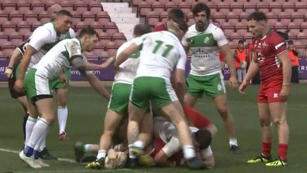 Ben Evans reaches through a crowd to score Wales' fourth try